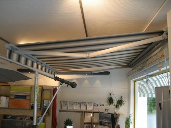 Moderne Markise mit Streifenmuster als Sonnenschutz in einer Ausstellung für Terrassen.