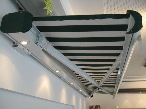 Elektrisch ausfahrbare Markise mit grün-weißem Streifenmuster und integrierten LED-Spots.